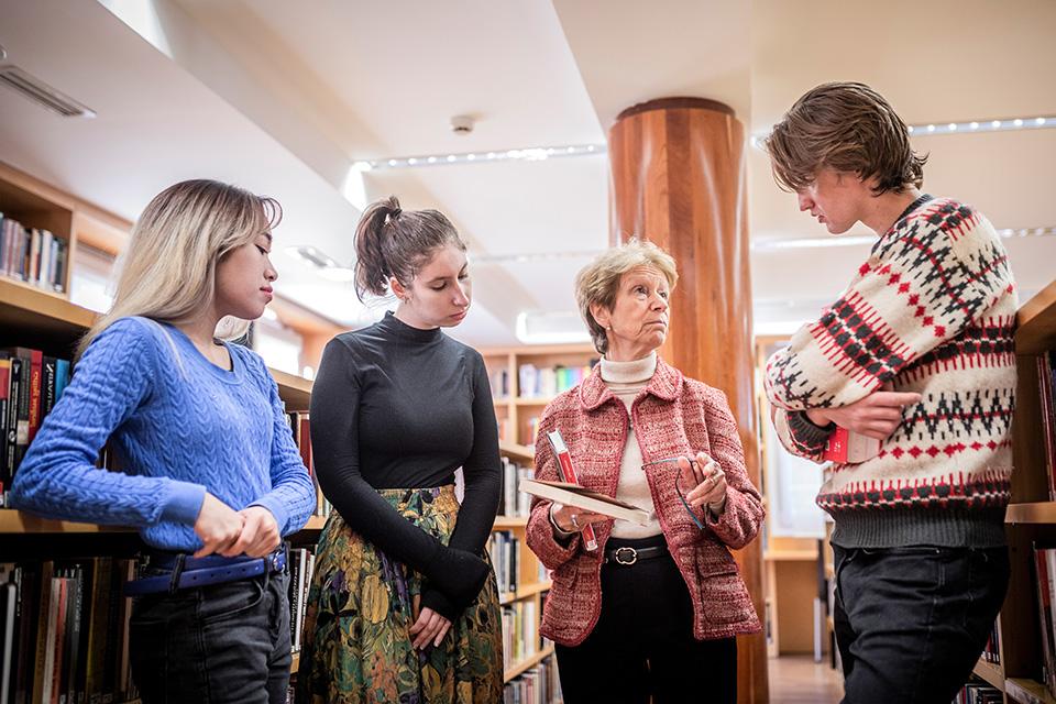 A professor discusses a book with students in a library